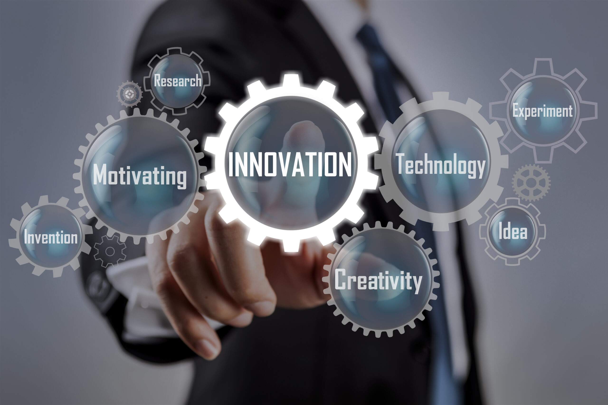 Business professional pointing at virtual gears labeled innovation, technology, and research